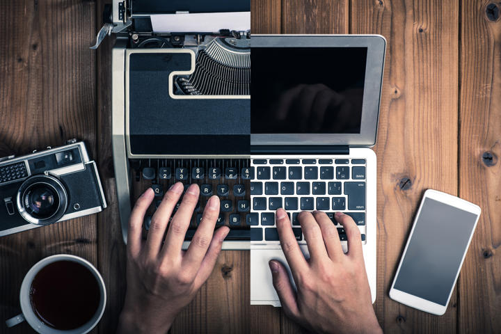 Half typewriter and old camera and other half laptop and smartphone