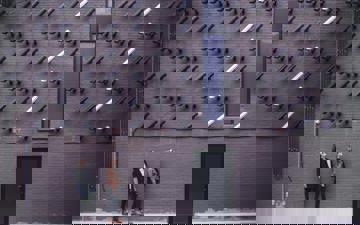 Outside wall with many security cameras pointing down at 2 people at a door